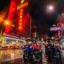 View of tuk-tuks and red bright neon signs at nighttime in Bangkok’s Chinatown