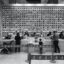 greyscale photo of tills at Lego store with customers interracting with cashiers, using the self checkout machines and kids playing around
