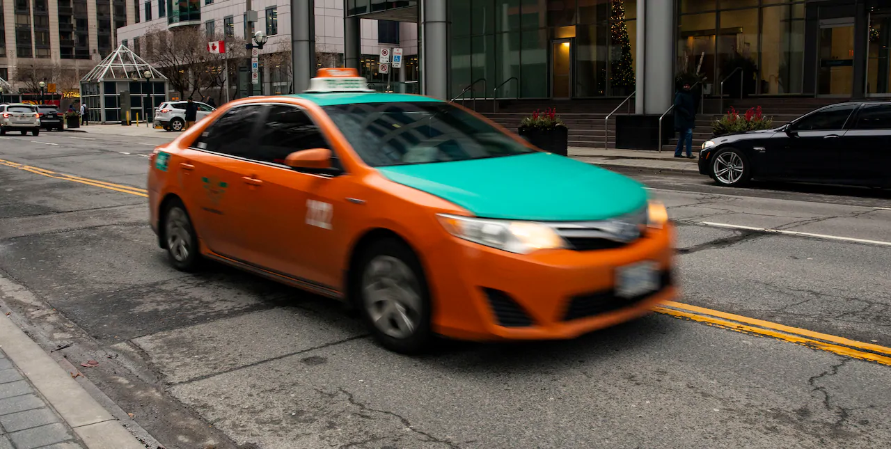 Taxicab downtown toronto blurred in-movement orange and turquoise taxi vehicle driving