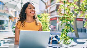 ethnic woman wearing yellow top woman working on laptop outdoors