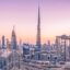 Panoramic view of Dubai’s skyline at sunset, featuring the iconic Burj Khalifa and modern high-rise buildings, symbolizing the city center accessible by Dubai Al Maktoum Airport taxi.