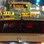 cream/light yellow taxis roaming the street at nighttime with a lighted signature taxi sing on their roof