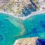 aerial view of clear blue waters near rocky formation and houses