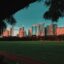 golden hour photo of city buildings and green grass under a blue sky
