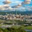 aerial photograph of Taipei city buildings green lawns, green trees and green mountains under a cloudy sky at daytime