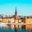 Stockholm city buildings in bright yellow and orange reflecting onto body of water in daytime. A perfect destination to explore after a comfortable taxi ride from Bromma Airport.