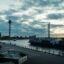 cloudy sky over high communications tower and loaded cargo ship by body of water