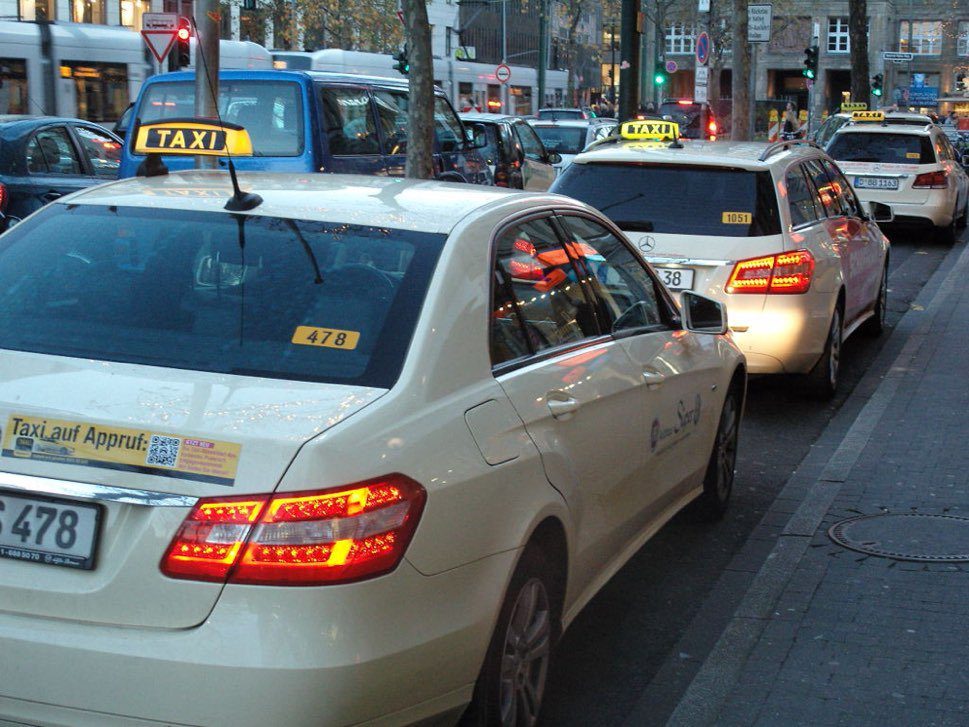 Dusseldorf Taxi pale yellow / cream taxis with a bright yellow and black lighted roof sign lining up by the pavement