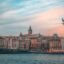 Scenic view of Istanbul’s Karaköy district at sunset, featuring the iconic Galata Tower rising above a cluster of historic buildings, with a seagull gliding across a pastel sky over the Bosphorus — a picturesque welcome often experienced by travelers taking an Istanbul Airport taxi into the city.