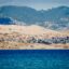 calm blue waters near small houses and a mountain