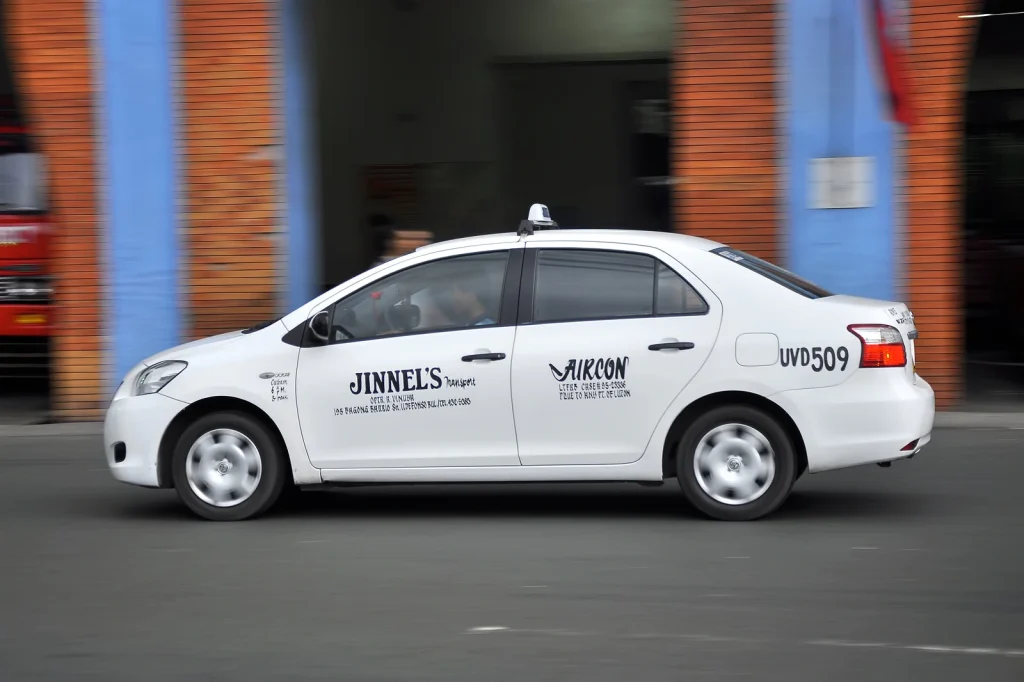 white vehicle with a signature taxi roof sign on a blurred background driving in the street