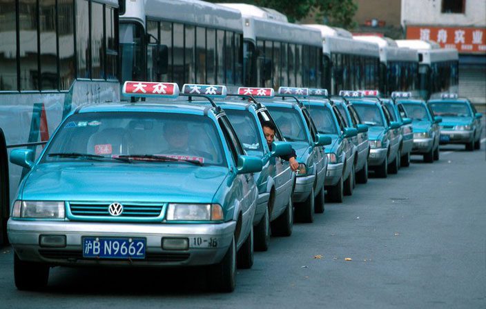 Shanghai taxi denim blue taxi cabs with a red or blue roof light/sign queuing up in the street
