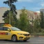 Yellow taxi roaming the street with a signature sign on the roof and 'taxi' sticker on the side
