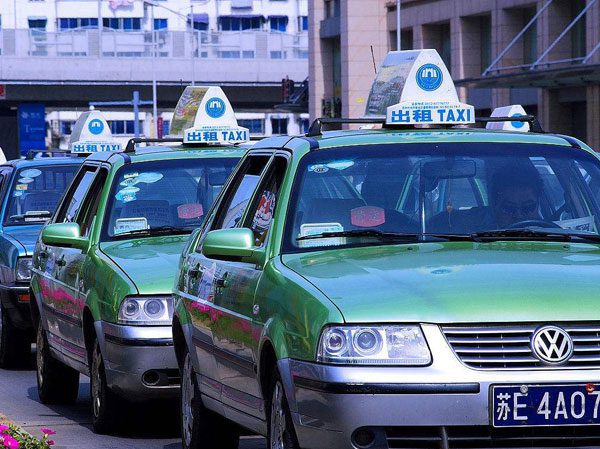 Chengdu taxi green taxis lining up by the pavement with a signature taxi sign on their roof