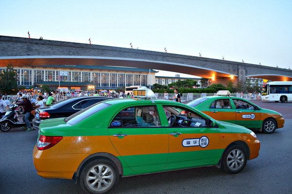 Xian taxi green and orange taxis with signature roof sign in the street