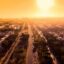 sun shining bright over the city's motorway, with green trees besides it and concrete buildings