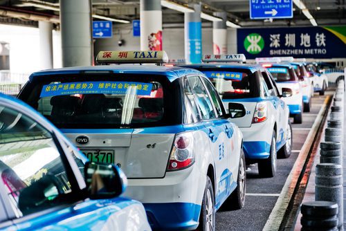 Shenzhen taxi, China white taxis with blue details and signature taxi sign on their roof lining up outside a train station