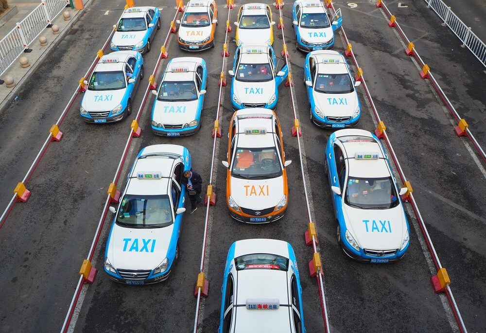 Xiamen taxi white taxis with orange or blue details and painted taxi wording at the front parked up