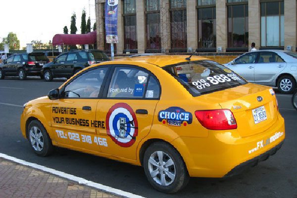 Siem Reap taxi yellow taxi wsith numbers and wording on it by the pavement