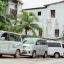 white minivan taxis parked up in front of white houses and palm trees