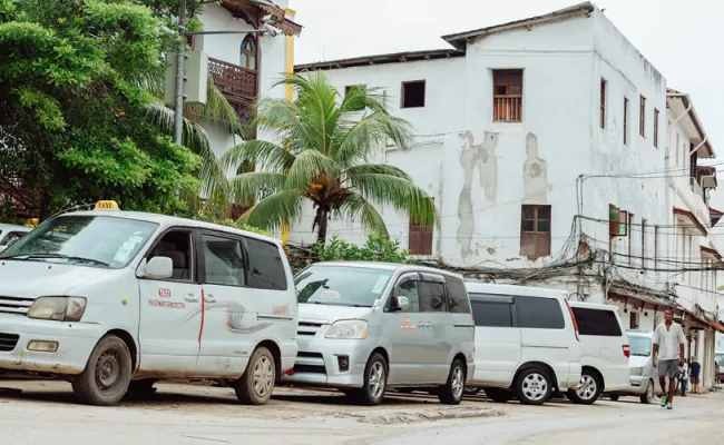zanzibar taxi white minivan taxis parked up in front of white houses and palm trees