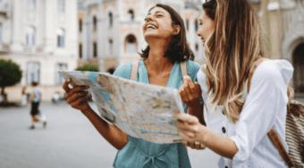 two young female travellers looking at map and laughing