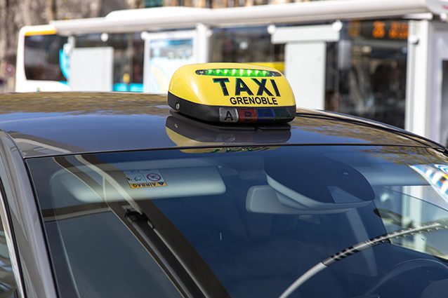 Taxi-Grenoble black vehicle with yellow taxi grenoble sign on the roof