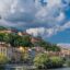 colourful concrete buildings and green trees under a cloudy sky in daytime by body of water