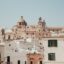 focused shot of old building facades in white and pale peach colours with dark coloured windows