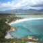 drone shot of a seashore next to a green jungle