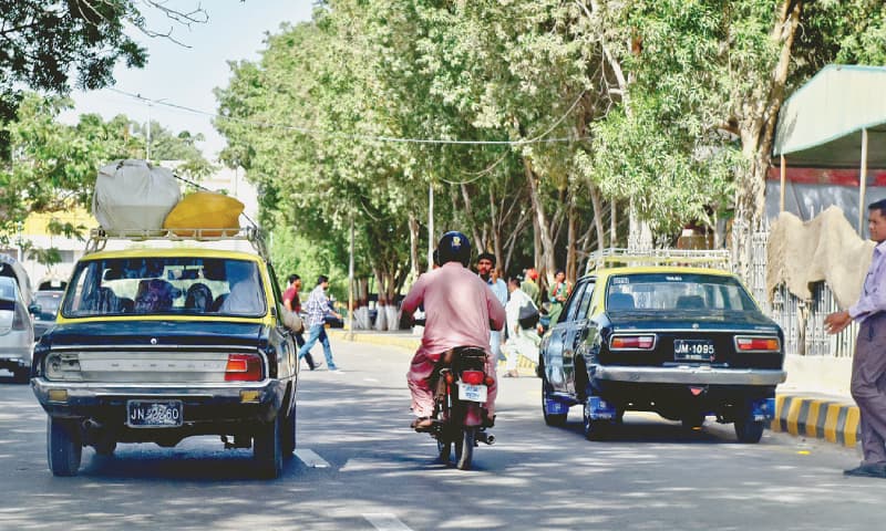 islamabad taxi two black vehicles with a yellow roof and baggage racks on top in traffic