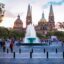 The Plaza de la liberacion in Guadalajara, Mexico, with a large fountain in front of a large ornate building with two round spires and two pointed ones.