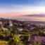Lush green trees and homes are seen under a blue and pink sunset sky in Kingston, Jamaica.