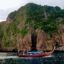 A traditional wooden fishing boat moored in from of a small limestone island.