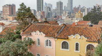Old houses with new skyscrapers in the background and grey skies above, Bogota, Colombia.