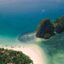 An aerial view of a white sand beach on an island with turquoise water and another smaller island just off the shore