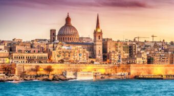 A view of the old city of Valletta in Malta with the ocean in the foreground.