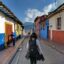 A backpacker walking down a historic street with colourful old buildings on either side.