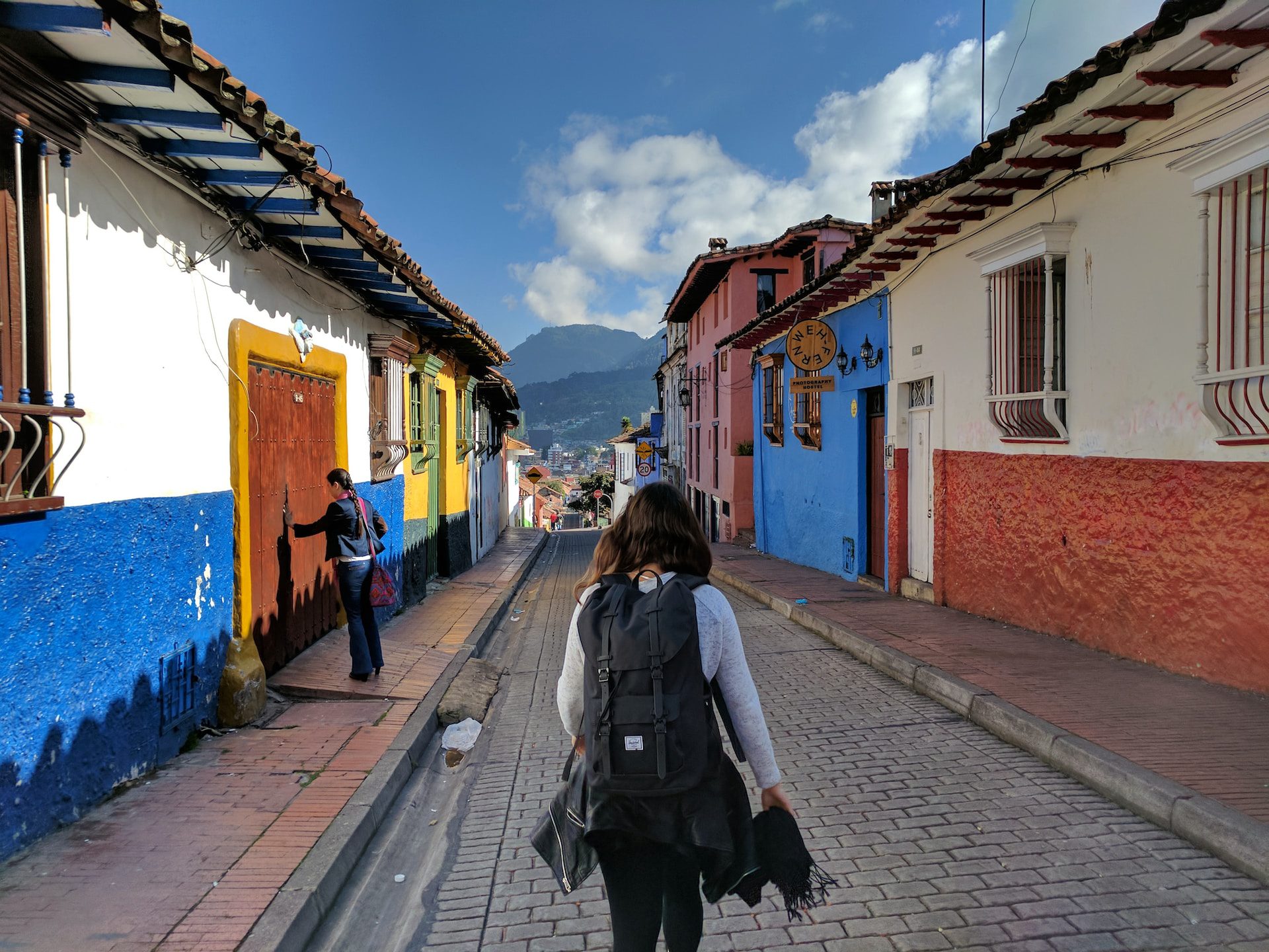 A backpacker walking down a historic street with colourful old buildings on either side.