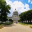 A park walkway lined with trees with the Mississippi State Capitol building at the end of the walkway.