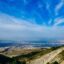 View from the peak of a mountain in the Sierra Nevada, overlooking a mountainous range and with blue skies above.