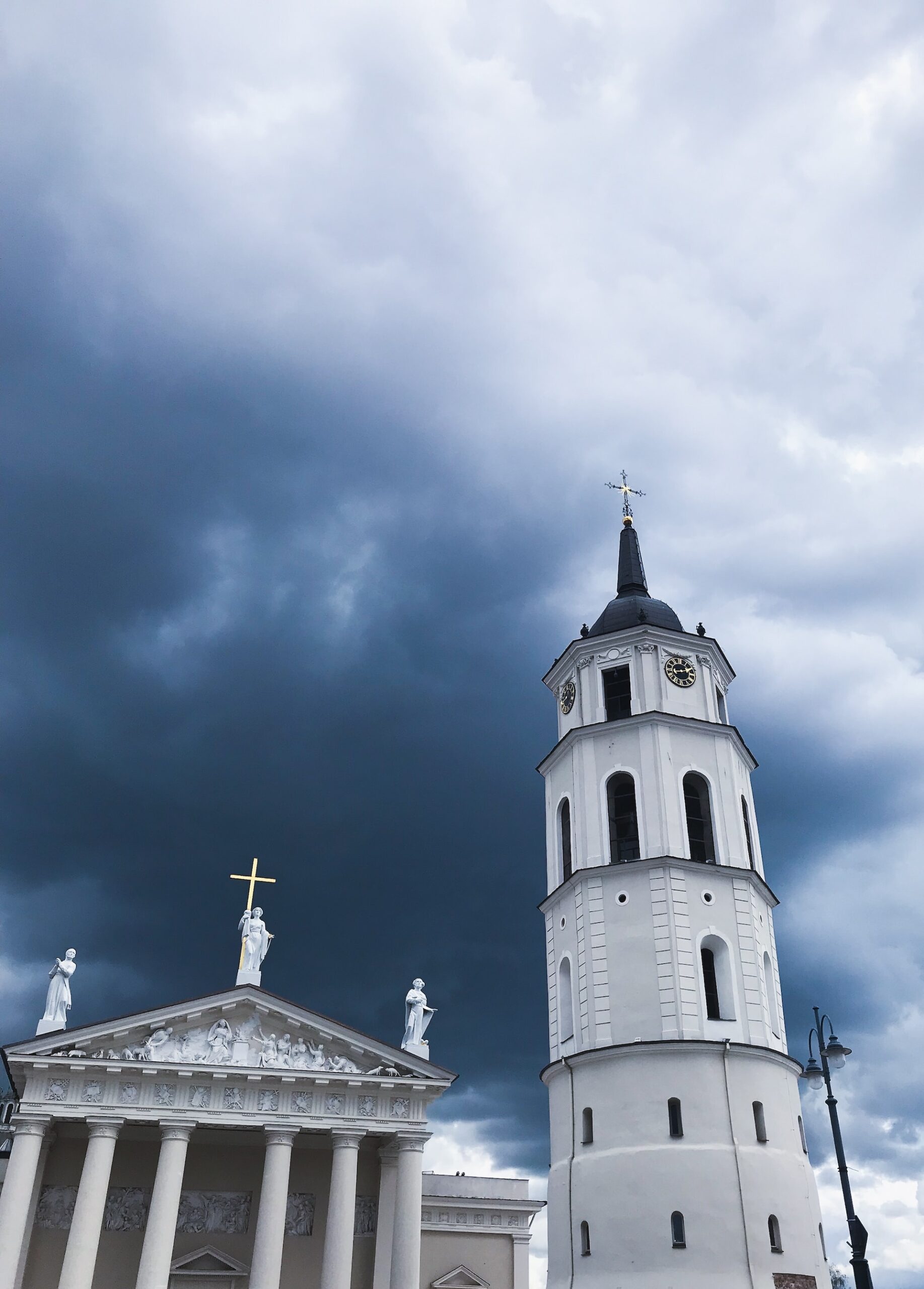 Vilnius church tower and cathedral with grey clouds above.