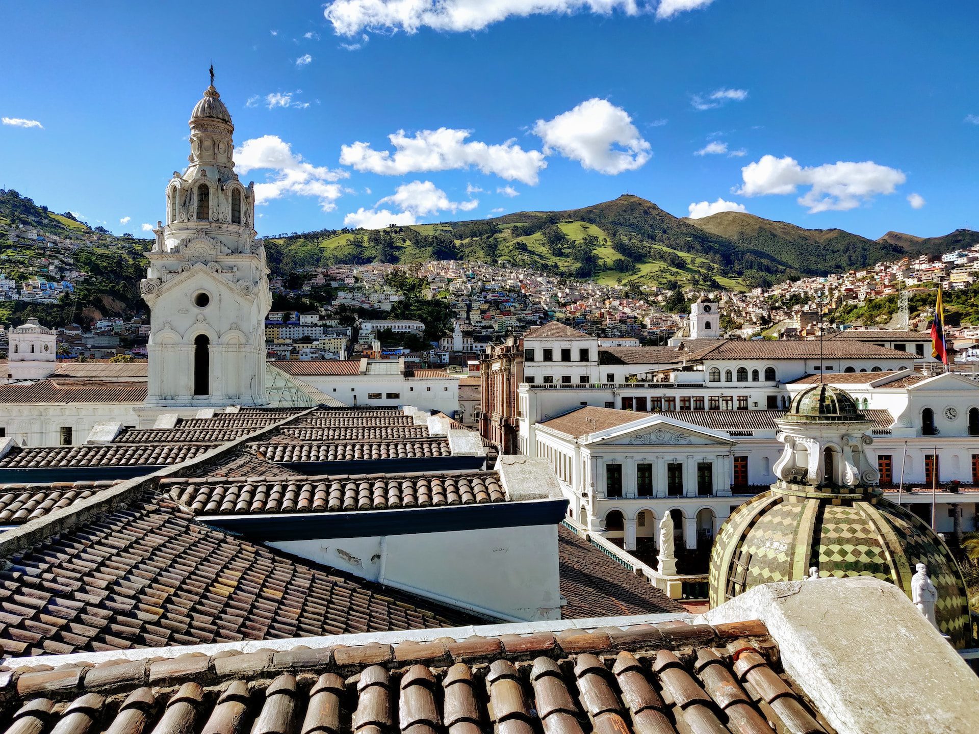 A view of the rooftops in the Old Town with a church tower and green hills in the background.