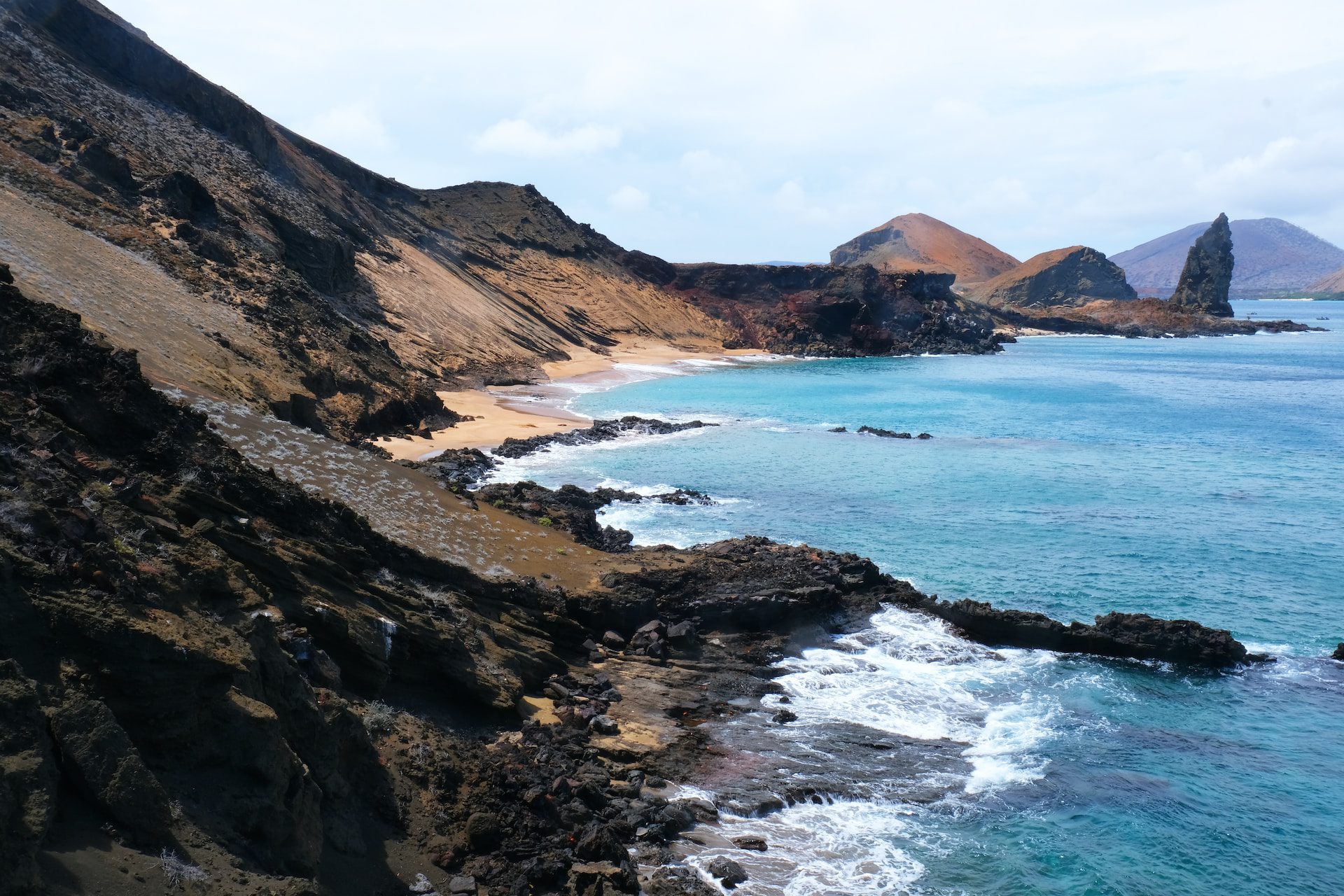 Rocky cliffs sweeping down into the blue sea.