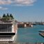 View of Genoa Port with a large ship docked on the left and blue waters with other ships on the right.