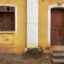 VIew of a wooden door and adjacent window on a yellow-walled house in Margao (Madgaon).