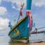 Photo the iconic wooden Thai boats, painted a blue colour with red ribbons tied to it and a yellow rim.