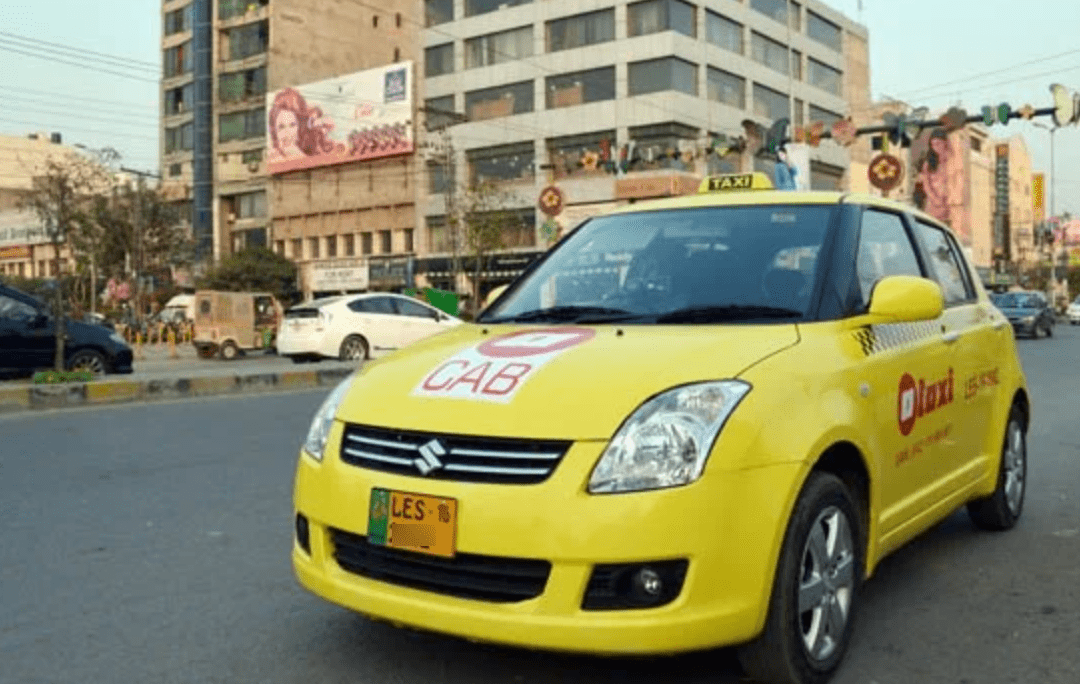 Lahore taxi service Front view of a yellow Lahore taxi on a street.