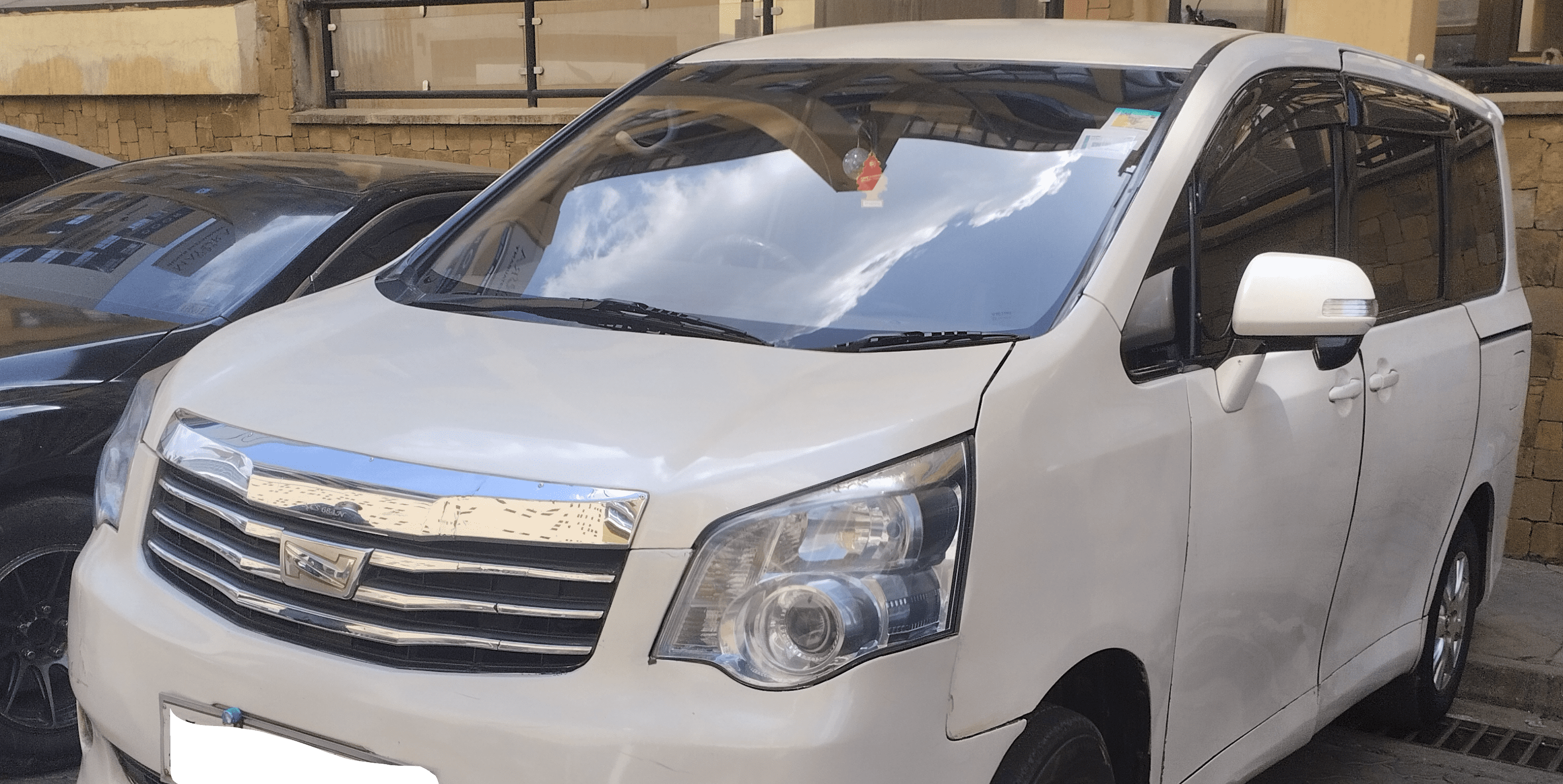 Front view of a biege minivan taxi at Nairoabi Airport, parked outdoors.