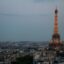 the eiffel tower lit up late in the evening under a cloudy sky